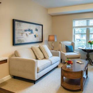 A cozy living room with a sofa, coffee table, and armchair next to a window.