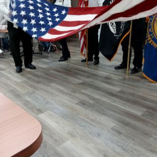 A group of individuals holding the American flag and military colors during a ceremonial event.