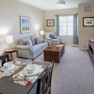A cozy living room featuring a sofa and dining table, with tasteful decor and natural light.