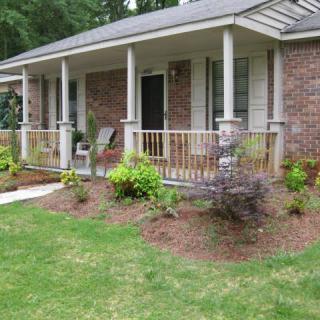 A brick house with a front porch and landscaped garden.