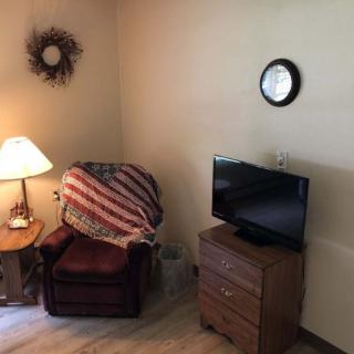 A cozy living room corner with a chair, lamp, TV, and wall decorations.