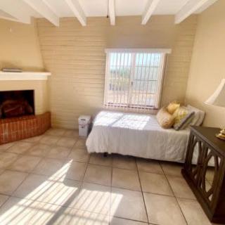 A cozy bedroom featuring a single bed by a window, a fireplace, and tiled flooring.