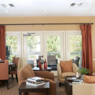A cozy living room with armchairs, a coffee table, and large windows adorned with red curtains.