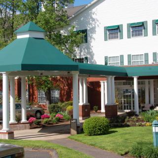 The entrance of a hotel with a green roof and landscaped garden.