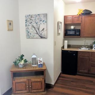 A cozy kitchen corner with a wooden cupboard, decorative items, and a wall painting.
