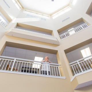 A person looking over the railing in a multi-level building atrium.