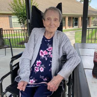 A cheerful elderly woman enjoying some time outdoors in her wheelchair.