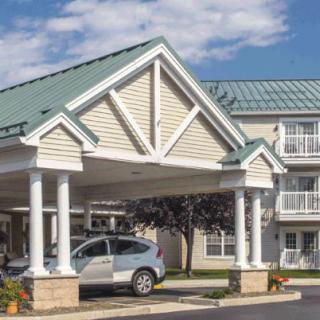 A hotel entrance with a covered carport and parked vehicle.