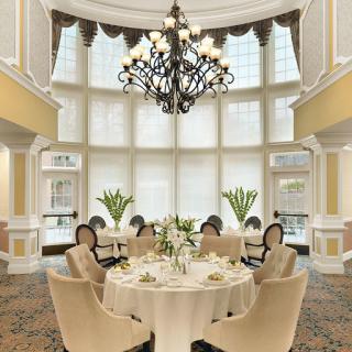 An elegant dining room bathed in natural light, featuring a sophisticated chandelier and beautifully arranged table.