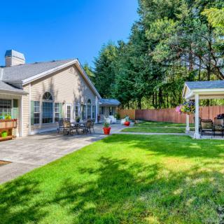 A beautiful backyard with a spacious patio area, well-maintained lawn, and cozy gazebo.