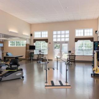 A well-equipped physical therapy and rehabilitation room with various exercise machines and parallel bars.