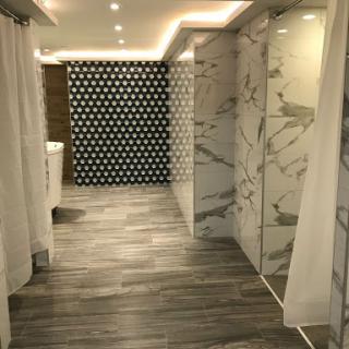 A stylish and modern bathroom featuring marble walls, wooden flooring, and unique patterned tiles.