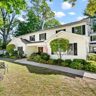 A two-story residential house with well-maintained landscaping and a green lawn.
