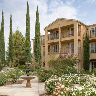 A well-landscaped apartment complex with a fountain and tall trees.
