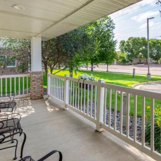 A cozy porch with outdoor seating overlooking a garden and street.