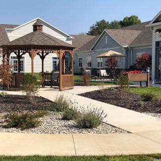 A landscaped garden with a gazebo and pathway surrounded by houses.