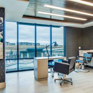 A modern office space with large windows offering a city view, featuring sleek furniture and a stylish design.