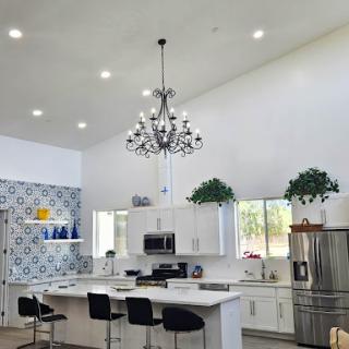 A stylish modern kitchen featuring sleek white cabinetry, a beautiful chandelier, and blue decorative elements.