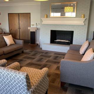 A cozy living room with a modern fireplace, sofas, and an armchair.
