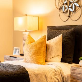 A cozy bedroom setting with stylish decor, featuring a bedside lamp and plush pillows.