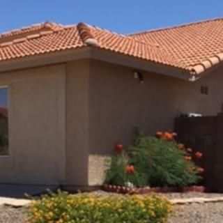 A suburban house with a terracotta roof and garden in a desert landscape.