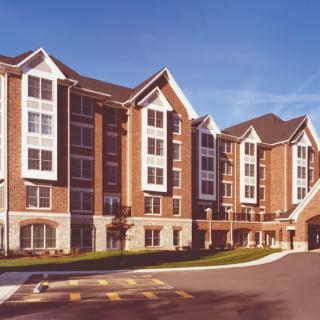 A modern residential apartment building with brick exterior and multiple windows.