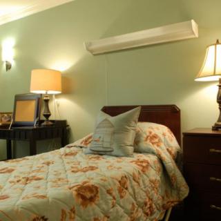 A cozy bedroom with a single bed and warm lighting.