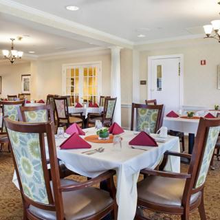 A well-decorated dining room with neatly arranged tables and chairs, featuring elegant place settings and ambient lighting.