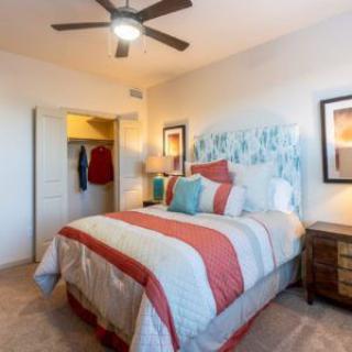 A cozy bedroom with a neatly made bed, stylish decor, and a ceiling fan.