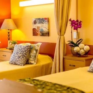 A cozy bedroom interior featuring warm colors, comfortable pillows, and a delicate orchid on the nightstand.