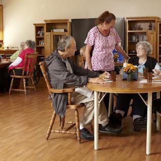A caregiver interacting with elderly residents in a nursing home setting.
