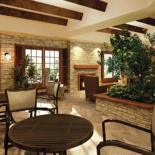 A cozy interior space with brick walls, wooden beams, and a seating area surrounded by plants.
