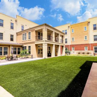 A beautifully designed residential courtyard featuring a lush green lawn and modern building architecture.