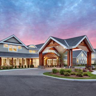 A beautifully designed residential building with a spacious driveway, set against a vibrant sunset sky.