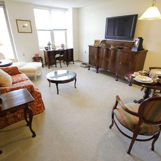 A cozy living room with antique furniture and a flat-screen television.