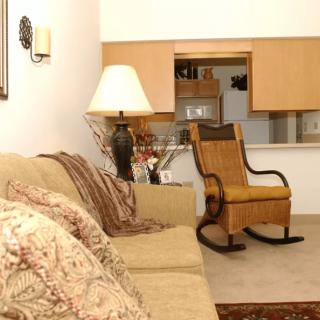 A cozy living room featuring a sofa, lamp, and rocking chair with a warm, inviting ambiance.