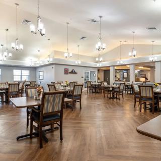 A spacious dining area with neatly arranged tables and chairs under elegant lighting.