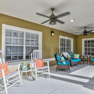 A cozy patio area featuring rocking chairs, colorful cushions, and ceiling fans.