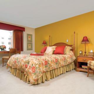 A cozy bedroom with a yellow accent wall, floral bedding, and warm lighting.