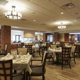 Empty restaurant dining room with neatly set tables and warm lighting.