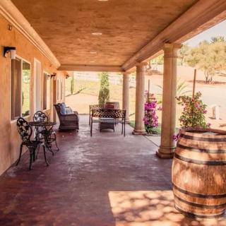 A rustic outdoor patio with barrels and seating area under a sunny sky.