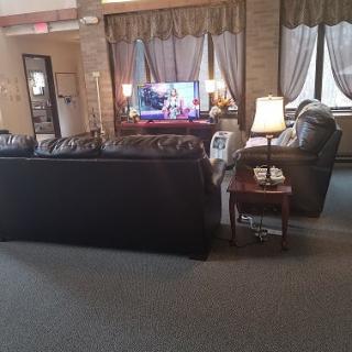 A cozy living room with sofas, a television, and lamps.