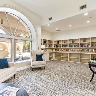A cozy library with armchairs, bookshelves, and a large window.
