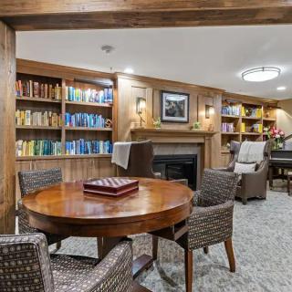 A cozy library room with bookshelves, a fireplace, and comfortable seating.