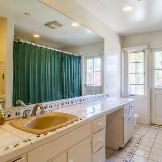 A spacious bathroom with a long countertop, large mirror, and green shower curtain.