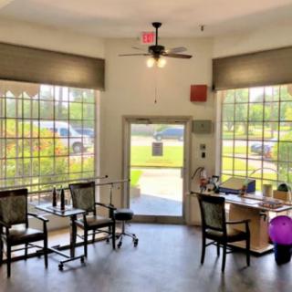A bright office interior with large windows, a desk, and seating area.