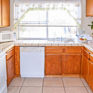 A bright kitchen with wooden cabinets, a dishwasher, and a large window.