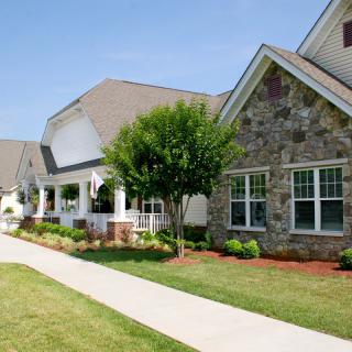 A charming residential house with a well-maintained front yard and stone exterior.