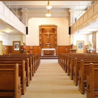 A serene view of a church interior featuring wooden pews and an altar.