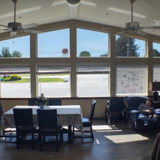 A spacious and well-lit indoor area featuring large windows, a dining table, and comfortable seating.